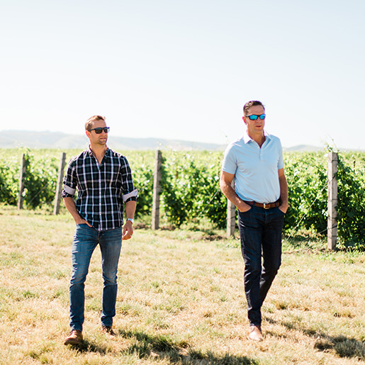 Two men walking through a vineyard